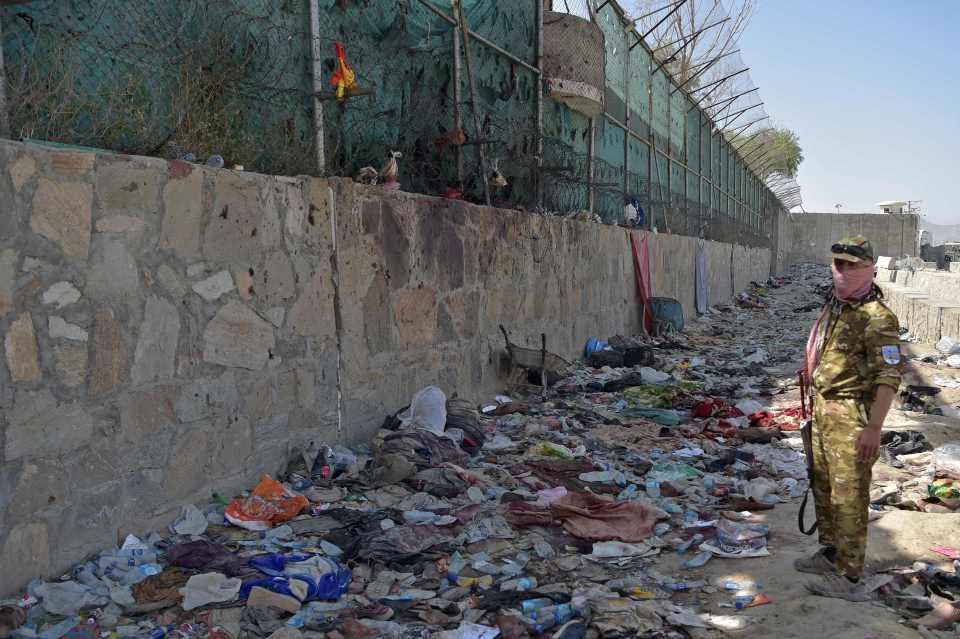 A Taliban fighter stands guard at the bomb site