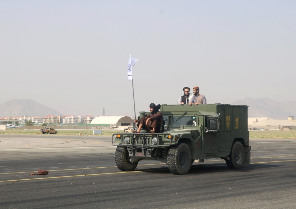 Taloban fighters ride on a Humvee as its tears across the tarmac at Kabul Airport