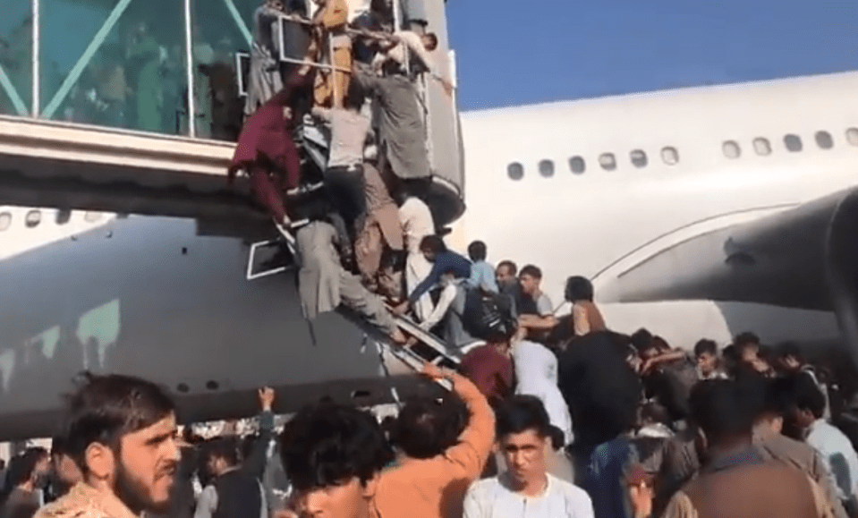 Desperate Afghanis climb stairs in a bid to get onto a plane at Kabul airport