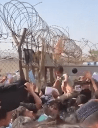 Terrified parents pass around a baby at the compound outside Kabul Airport