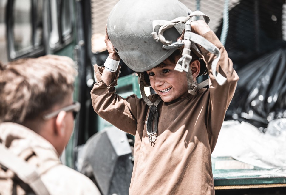 A US Marine handed a helmet to a child waiting to be evacuated from the airport