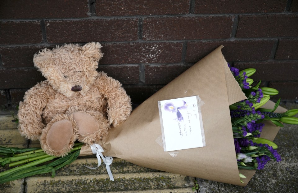 A teddy bear and flowers lay outside the OYO Metropolitan Hotel