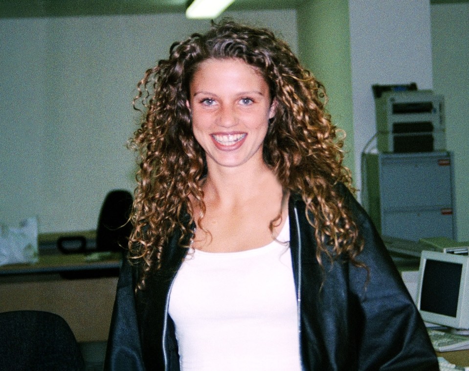 a woman with curly hair is smiling in front of a computer