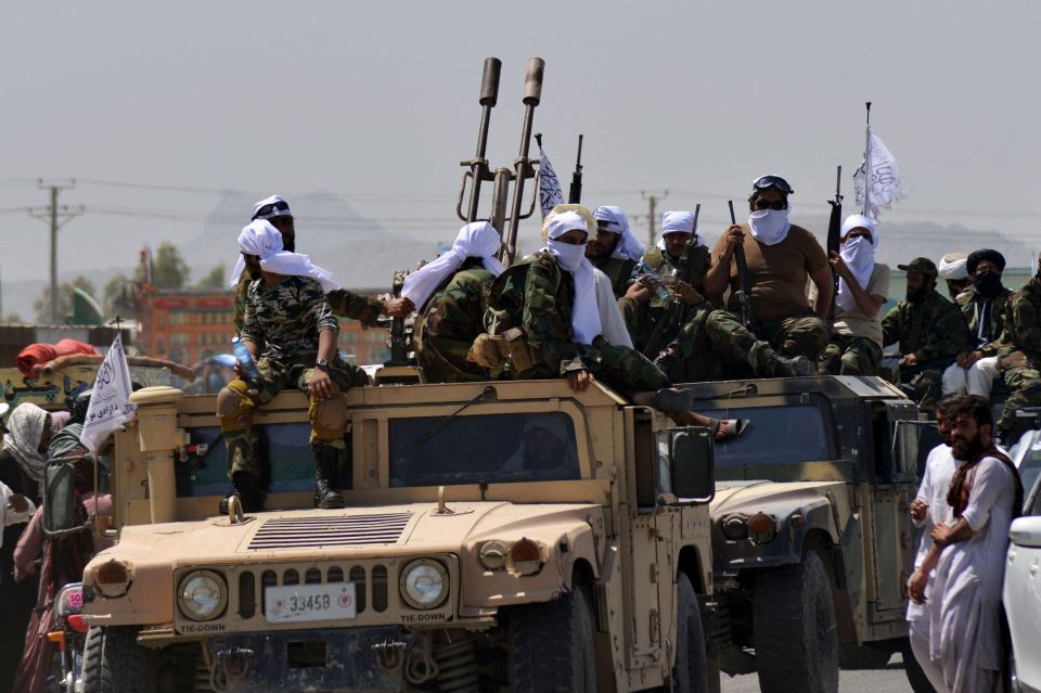 Taliban fighters atop Humvee vehicles stolen from the US backed government parade along a road to celebrate