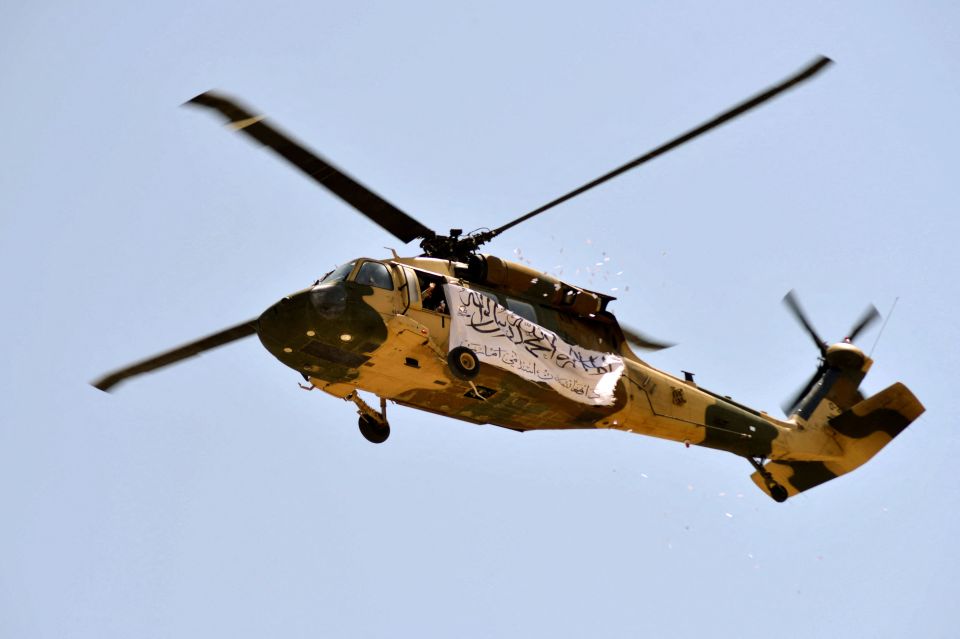 A helicopter seized by the Taliban is seen displaying their flag as it flies above of supporters gathered to celebrate the US withdrawal