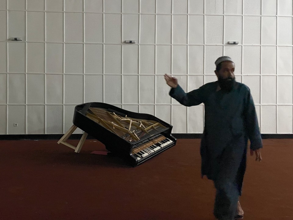 A Taliban guard inspects one of two grand pianos that have been destroyed at the government run recording studio