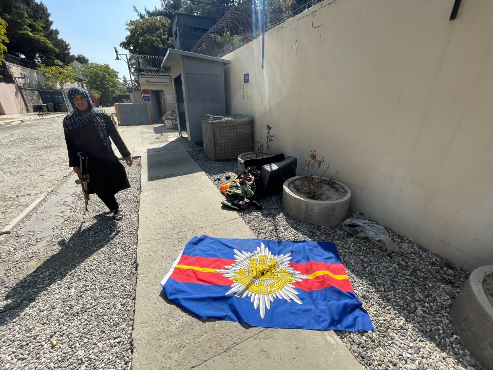 A Taliban guard passes the Royal Anglian regimental flag outside the deserted British Embassy