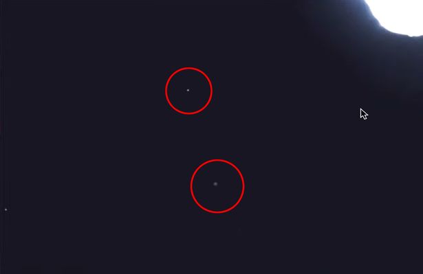 A screengrab of two unidentified objects shooting past the International Space Station