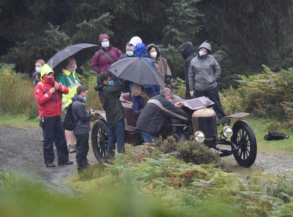 She was surrounded by crew with umbrellas as the heavans opened