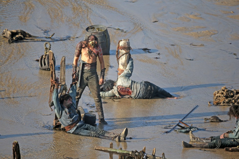 Battered and bloody extras are tied up on a muddy beach during filming for House of the Dragon