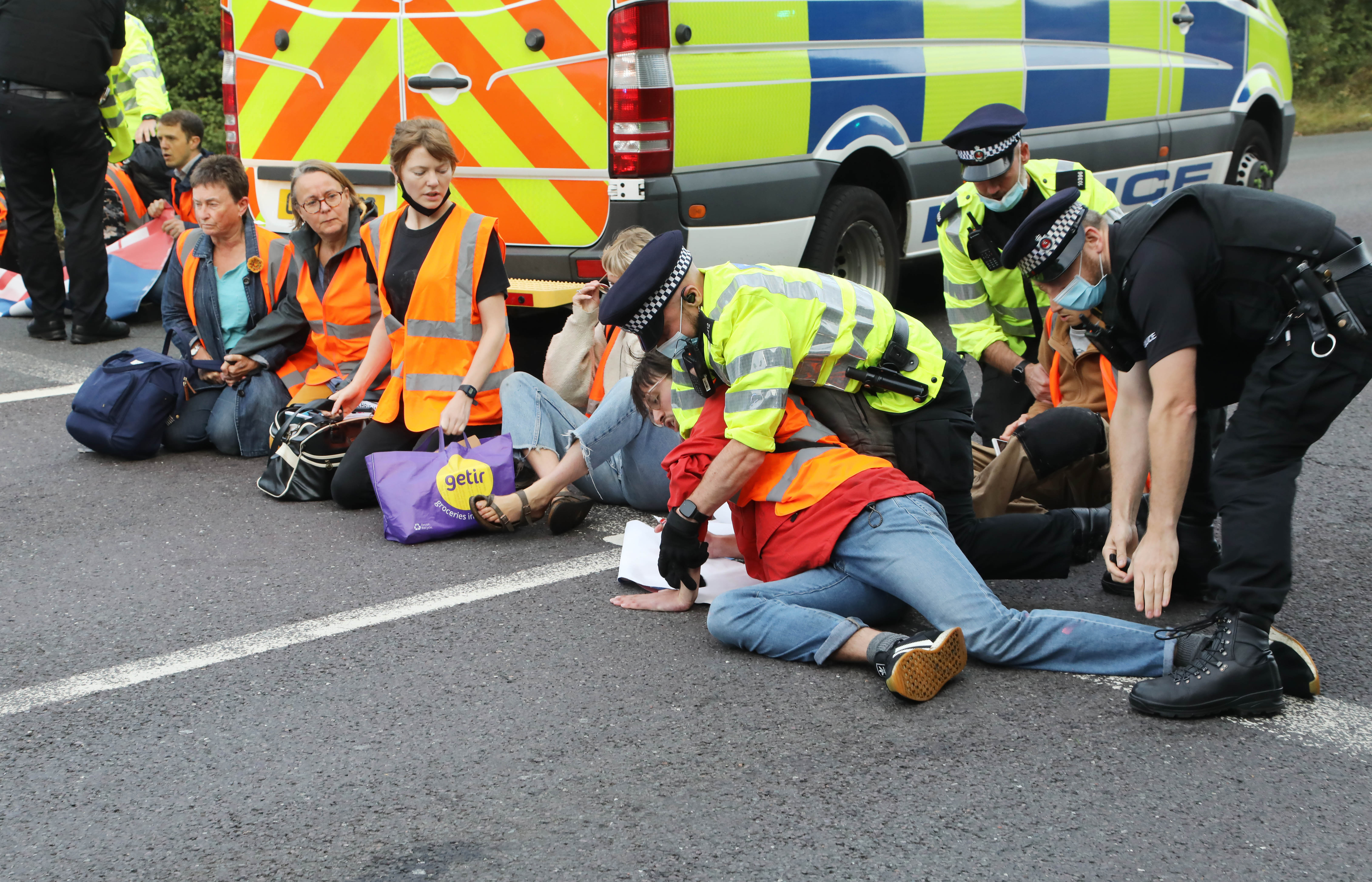 Police attempt to drag the protesters off the road