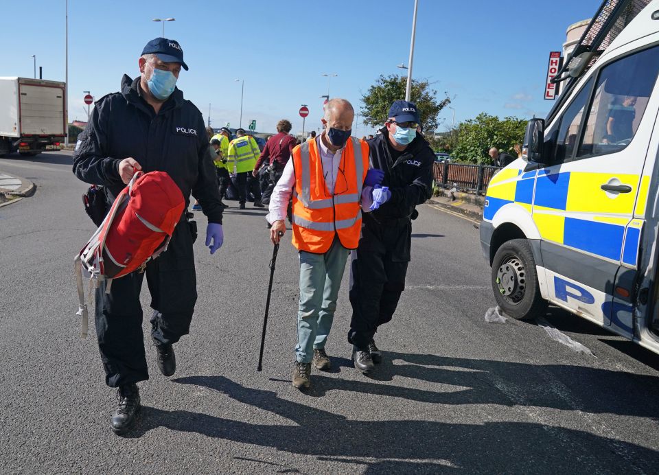 Cops escort a protester with a walking stick from the road in Dover