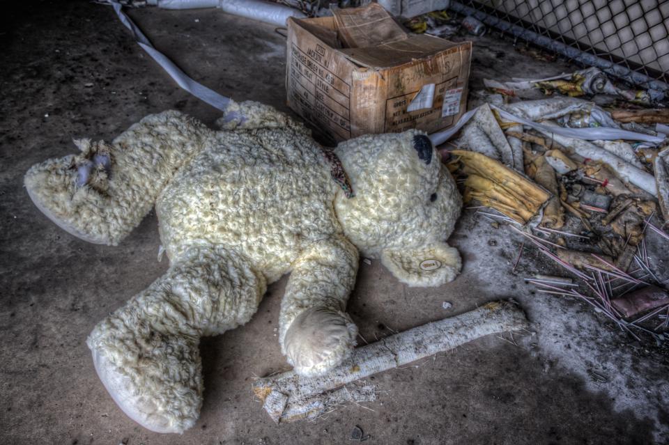 A child's teddy bear is left on the ground