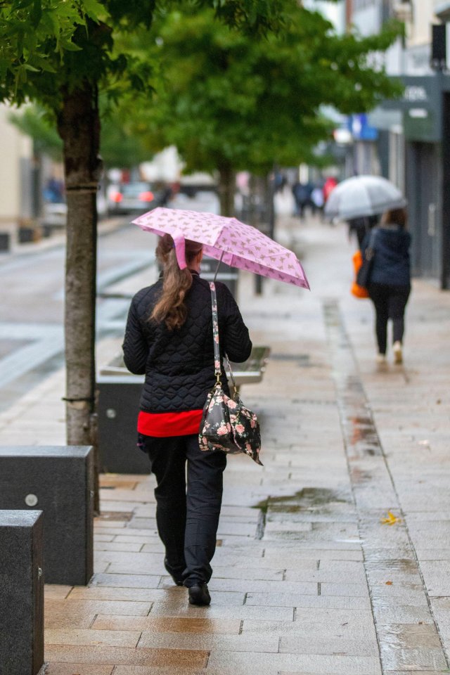 A woman shelters under an umbrella in Preston, Lancashire