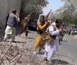 Taliban fighters fire their assault rifle into the air to break up the protesters