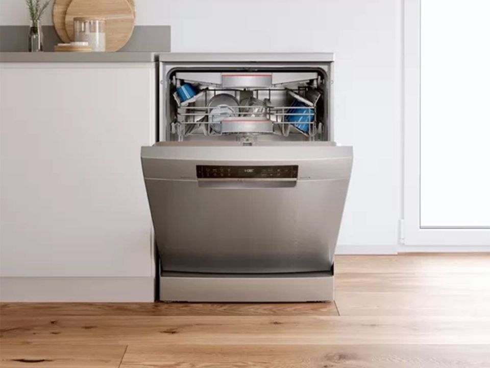 Freestanding dishwasher with open door, showing dishes inside.