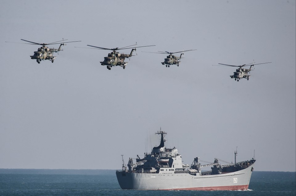 Helicopters flying over a huge Russian warship during the drills