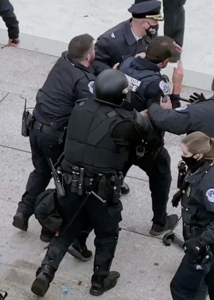 An injured officer is led away from the police line guarding the Capitol