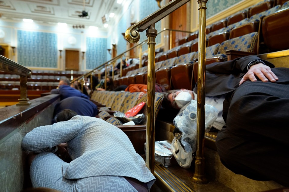 Representatives hide from protesters in the gallery of the House chamber