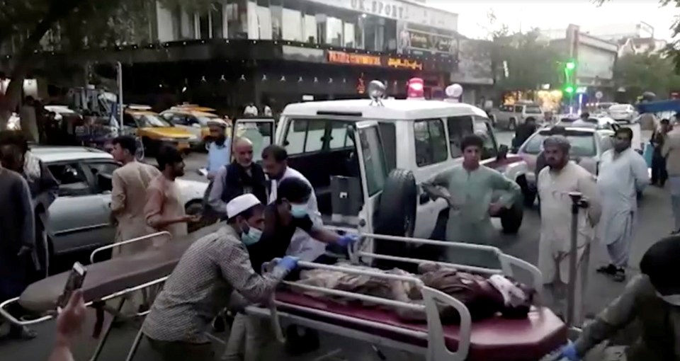 People carry an injured person to hospital after a suicide bomb attack at Kabul airport on August 26 that was claimed by ISIS