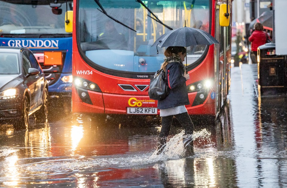 A commuter wades through rainwater in the capital