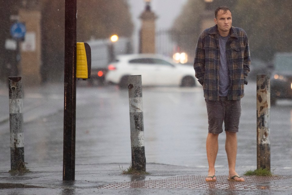 A man wears flip flops as he waits at a set of traffic lights outside London's Greenwich Park