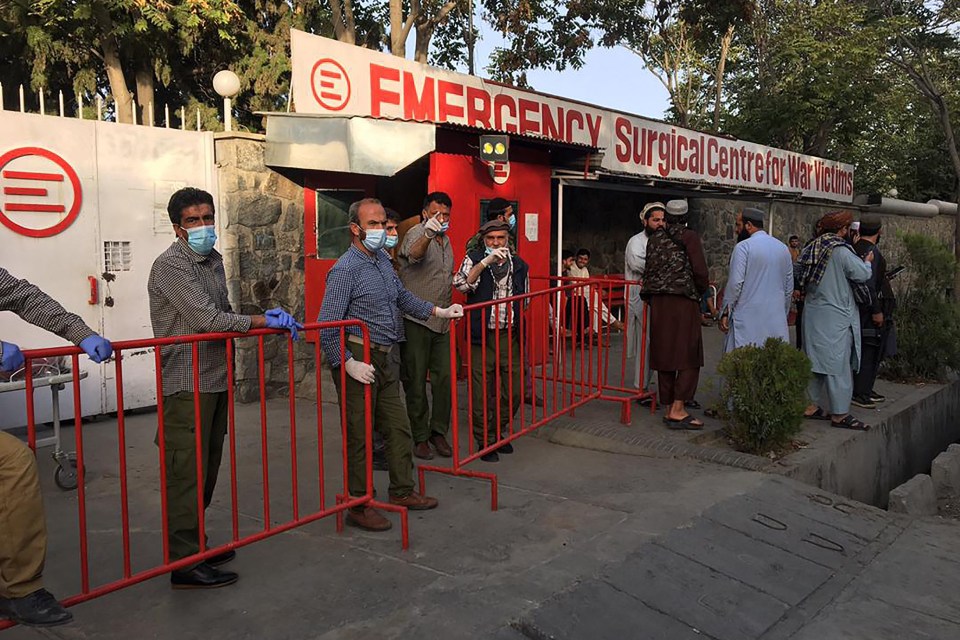 Afghan medical staff members stand at the entrance of a hospital as they wait to receive the victims of an explosion in Kabul