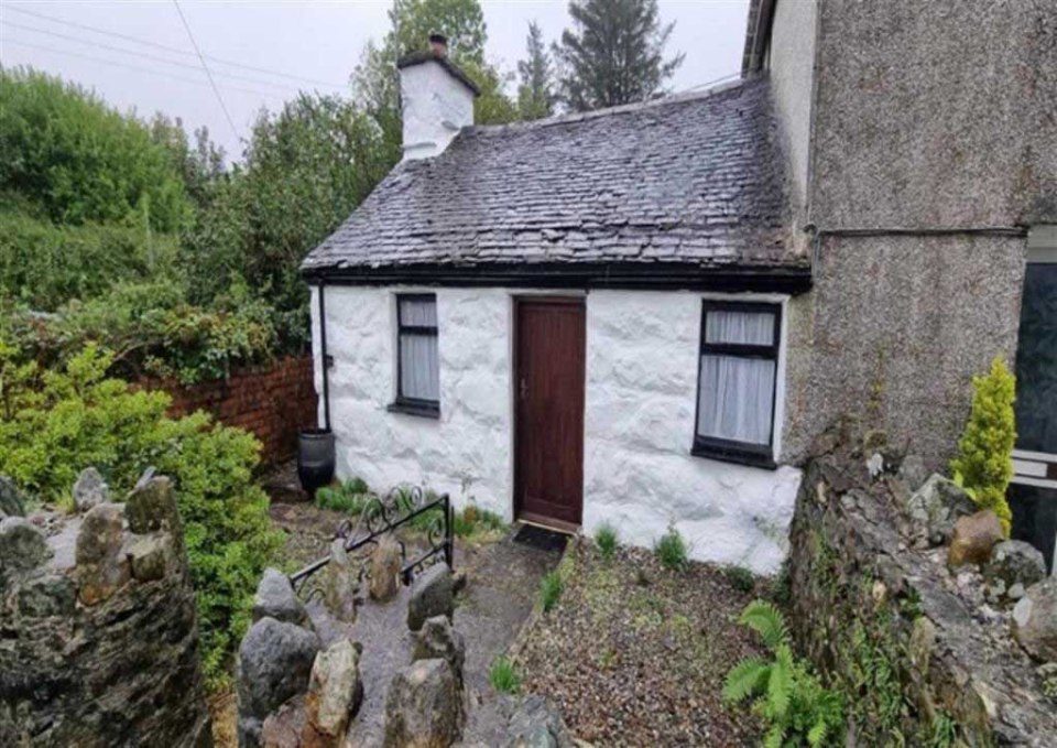 The little cottage sits next to a larger house and another cottage on the other side