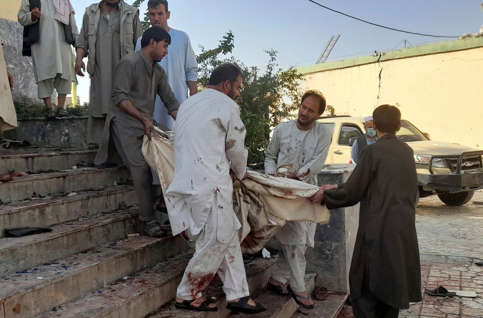 People carry the body of a victim from a mosque following the cruel bombing