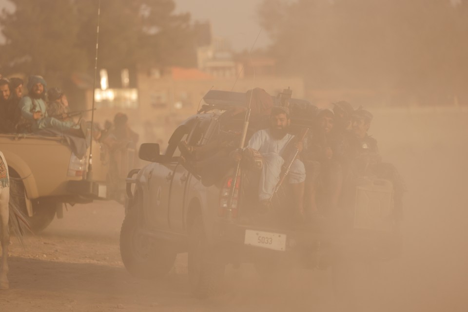 Taliban fighters arrive in the backs of pick up trucks