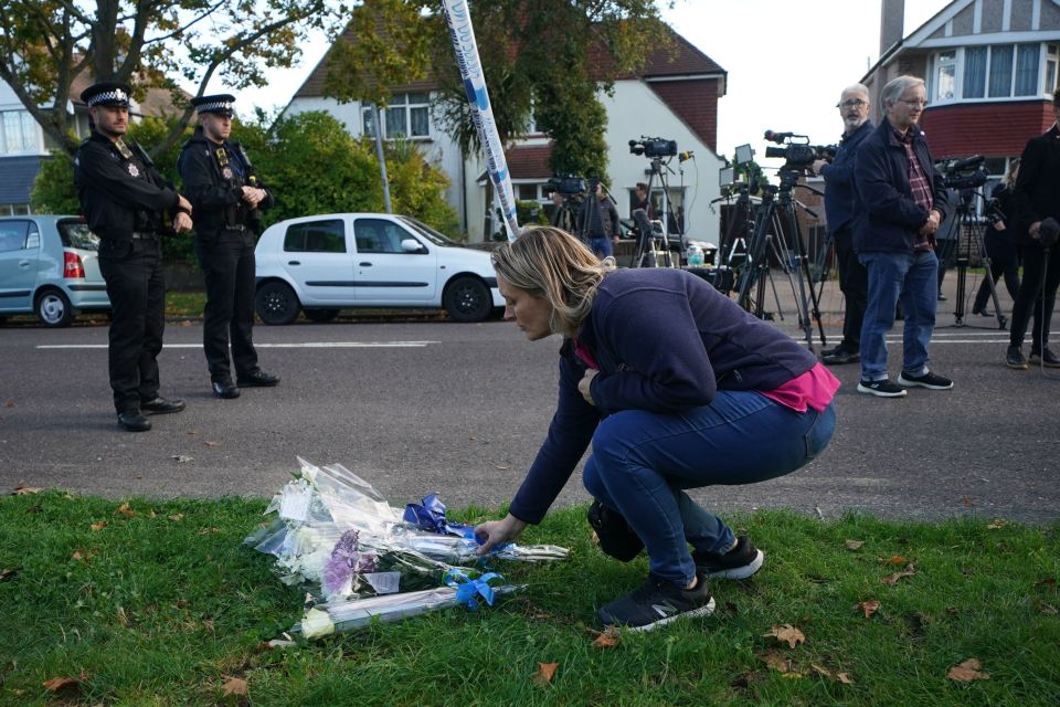 A woman leaves flowers close to the scene of the brutal attack