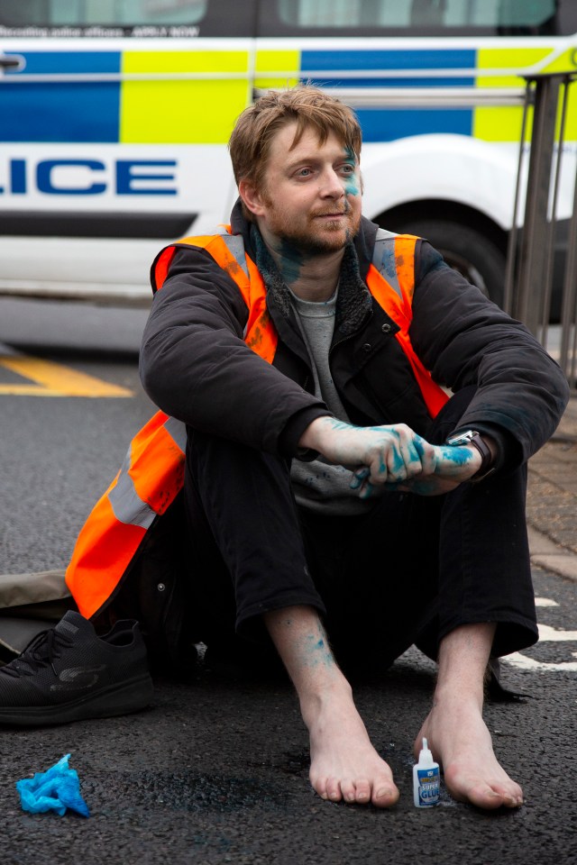 A protestor who was covered in ink poses with a bottle of superglue