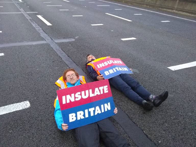 Two protesters lie in the damp road