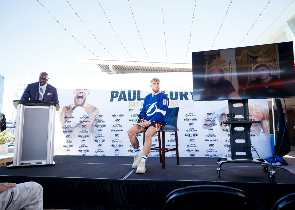 Jake Paul on stage with Tyson and Tommy Fury talking through Zoom