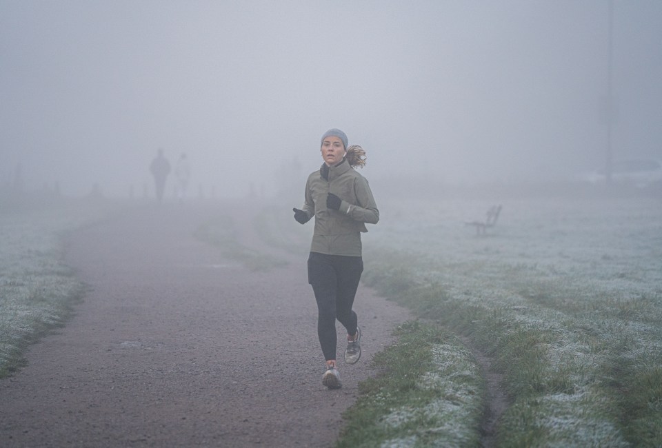 A jogger runs through fog in Wimbledon