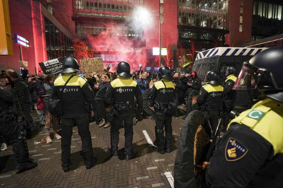 Riot police officers face protesters as they gather in the Hague on November 12