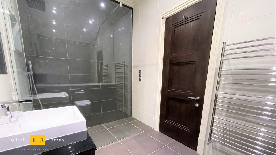 The bathroom features white walls, grey tiled flooring and a modern shower