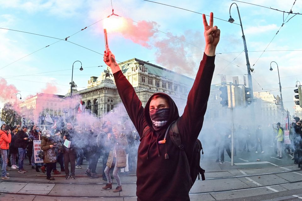 Demonstrators light flares during a rally held in Austria over Covid restrictions