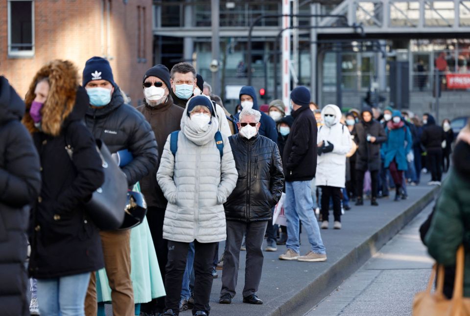 People wearing face masks stand in a long queue to get vaccinated in Hamburg