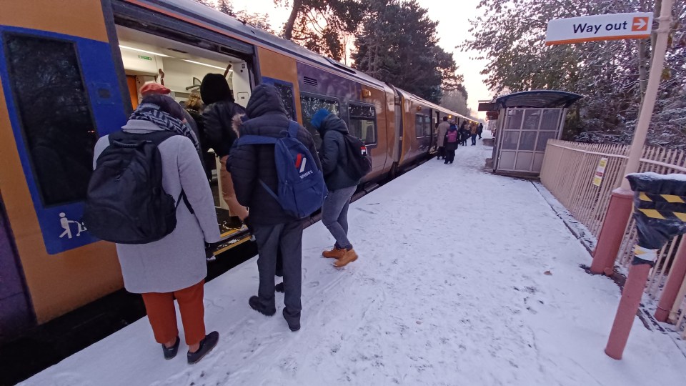 Commuters board a morning train in Birmingham, where some schools have closed due to the weather