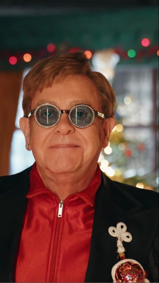 Ed takes holds up a series of cards, confirming the song’s release as Elton grins at his front door