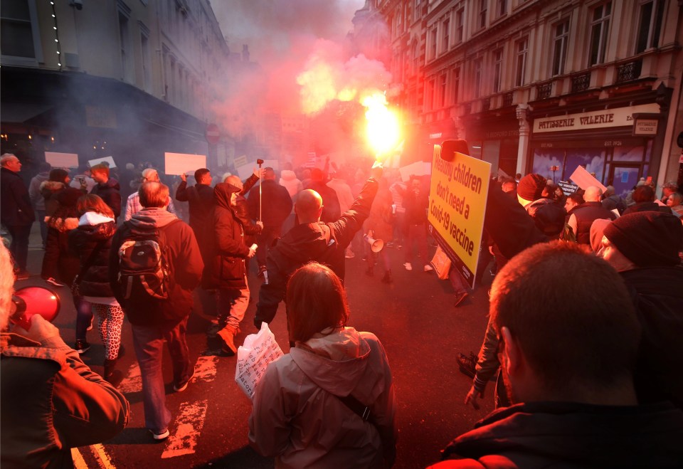 A protester lets off a flare as anti-vax demonstrators march across London last month