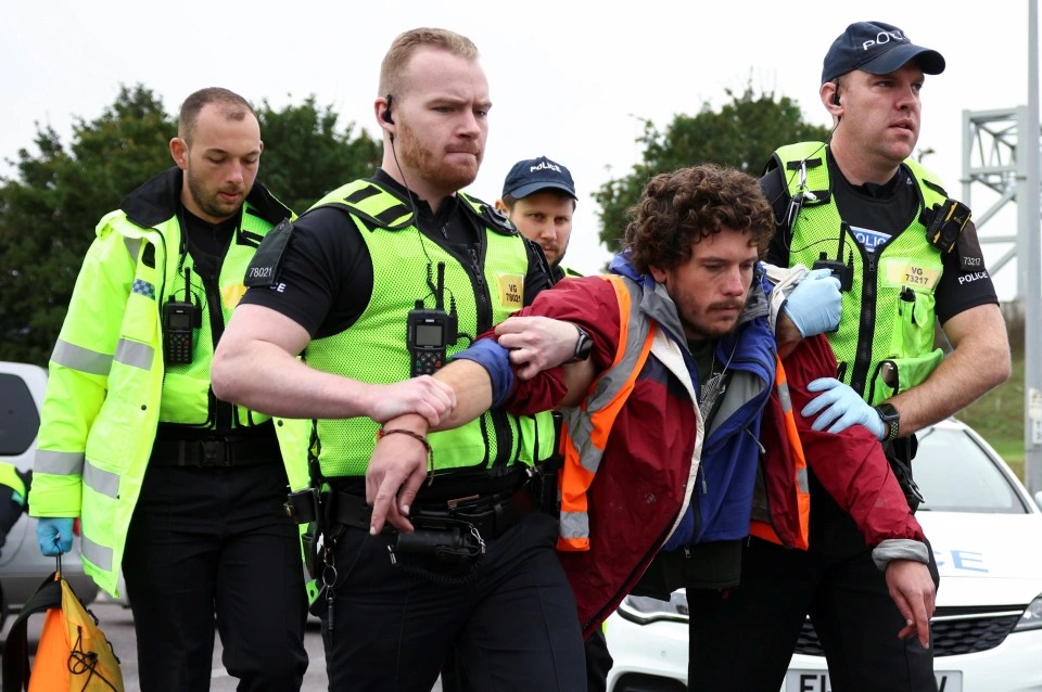 Police officers detain a man at a junction on the M25 in Thurrock, Essex