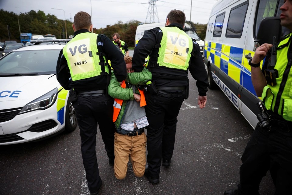 An activist is dragged away by two cops