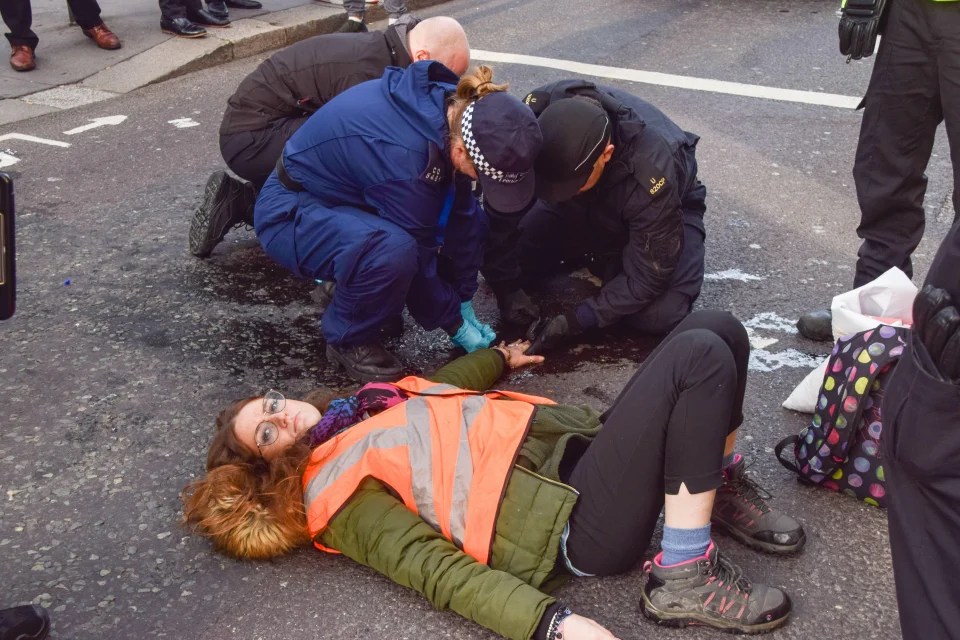 Police officers dissolve the glue on a protester's hand close to Liverpool Street Station, London