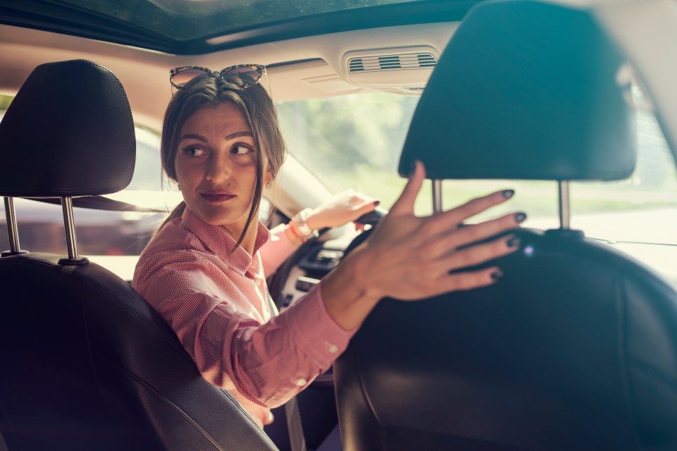 a woman adjusts the headrest of her car