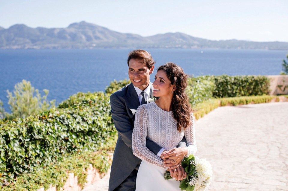 a bride and groom pose for a picture with the ocean in the background