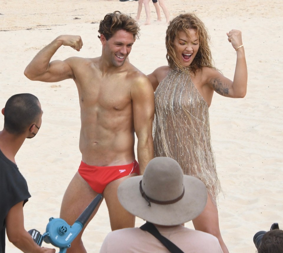 Rita was in this sparkly gold dress to pose with muscular lifeguards and even flexed her own guns