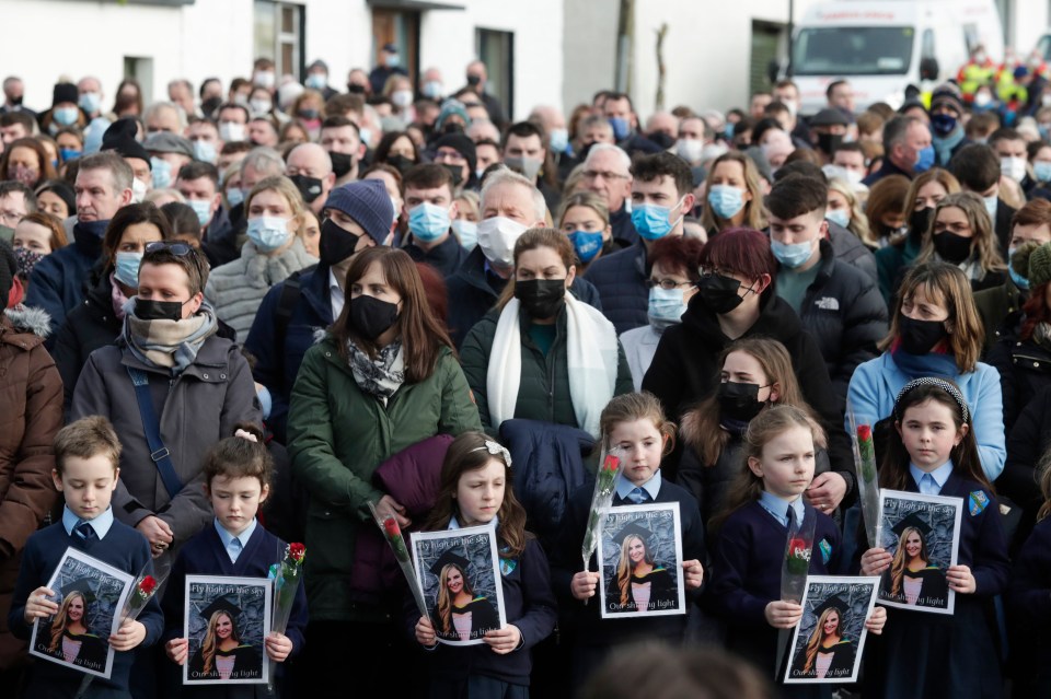 Pupils from Ashling Murphy’s class hold photographs of her and red roses outside St Brigid’s Church, Mountbolus