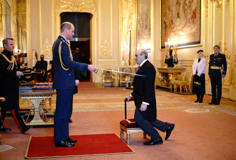 David Suchet kneels to be knighted by Prince William at Windsor Castle